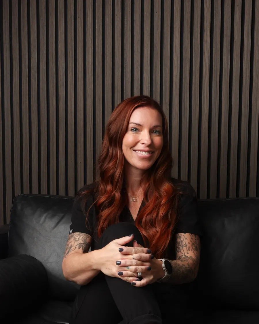 Sarah seated on a black leather sofa